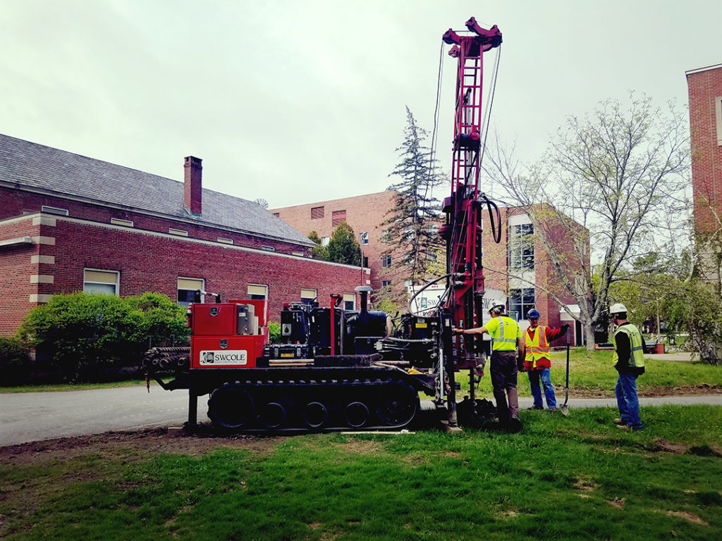 photo of a drilling rig being worked on by three workers