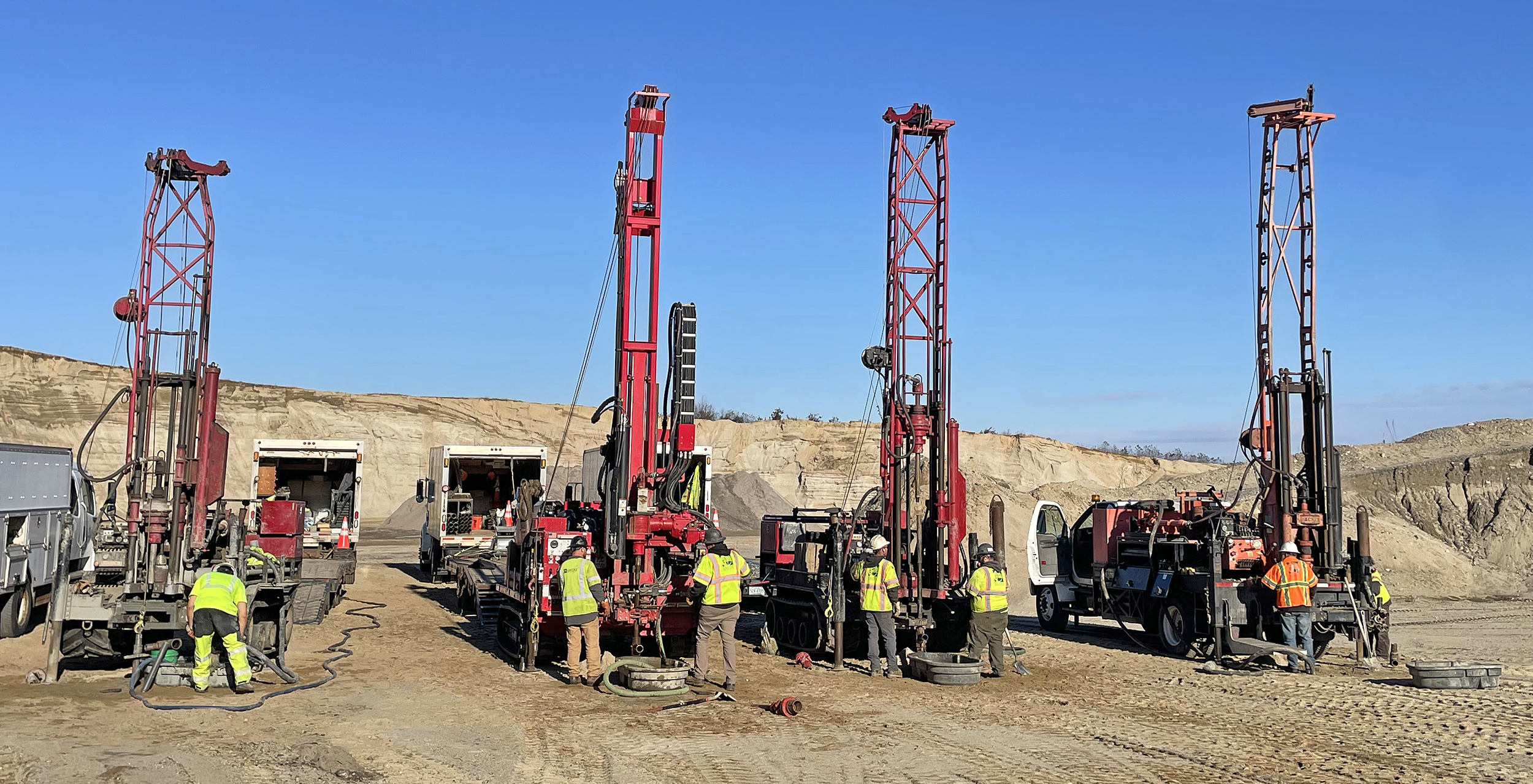 4 drill rigs side by side with people working on them