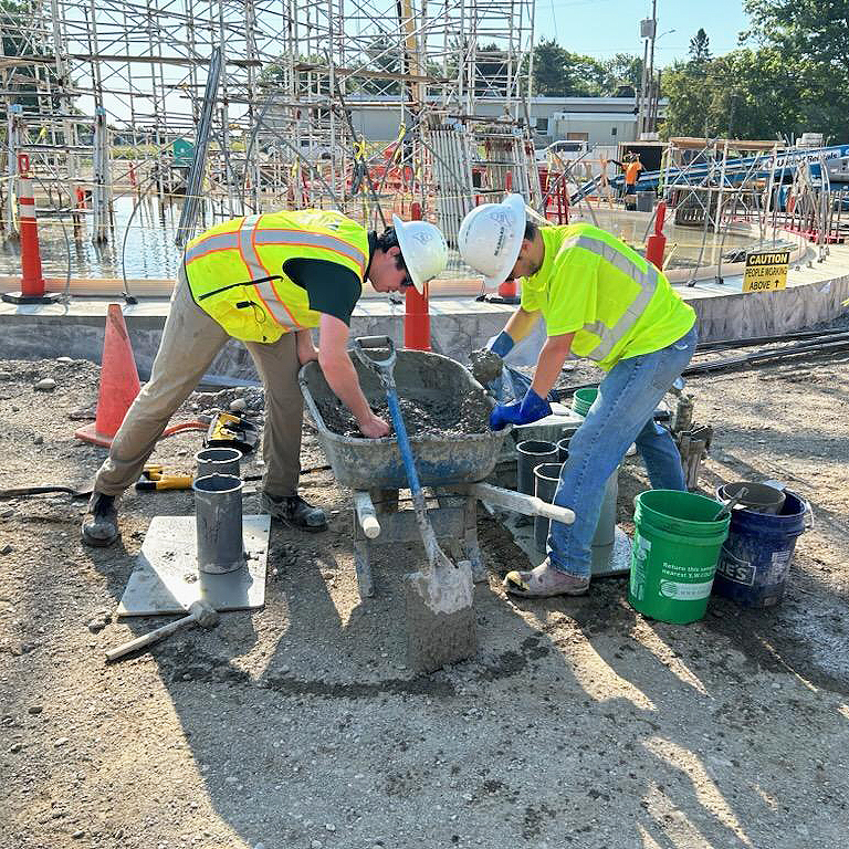 Two S.W. Cole team members filling cylinders for concrete testing.