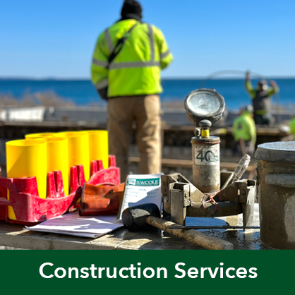 Concrete testing tools laid out on a table overlooking a construction site with people at work and the ocean beyond.