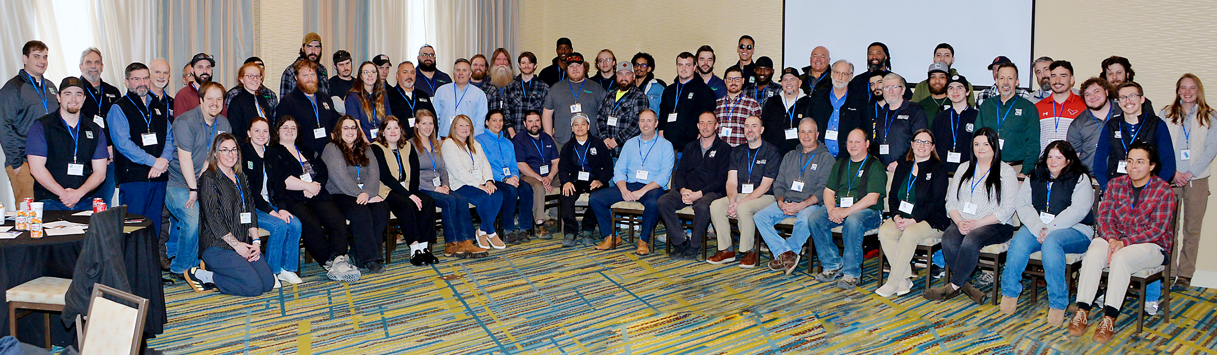 Large group photo of employees in an event center, some sitting and some standing.