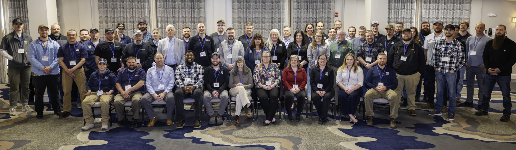 Large group photo of employees in an event center, some sitting and some standing