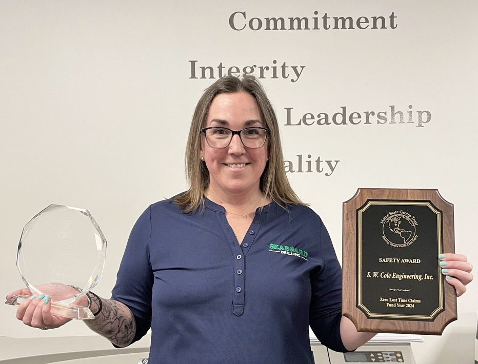 Director of Health and Safety Jess Smith smiling and holding two safety-related awards.
