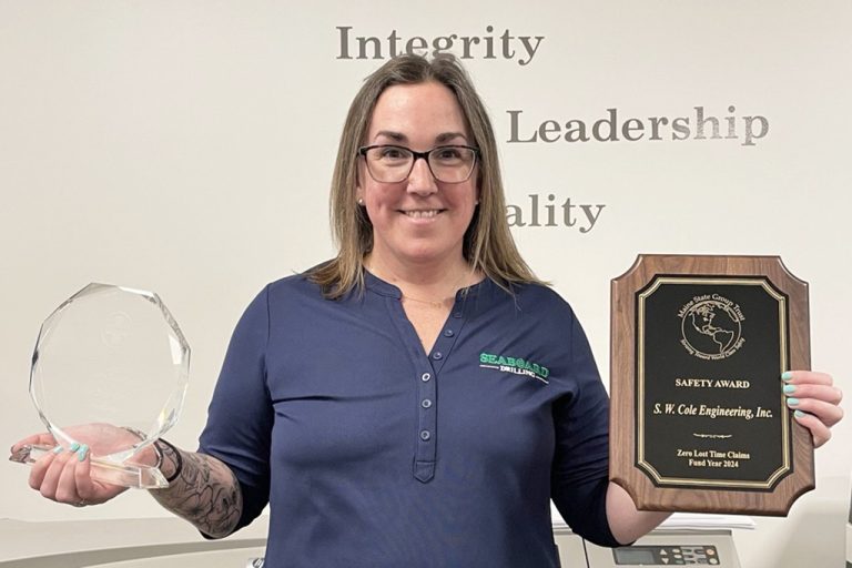 Director of Health and Safety Jess Smith smiling and holding two safety-related awards.