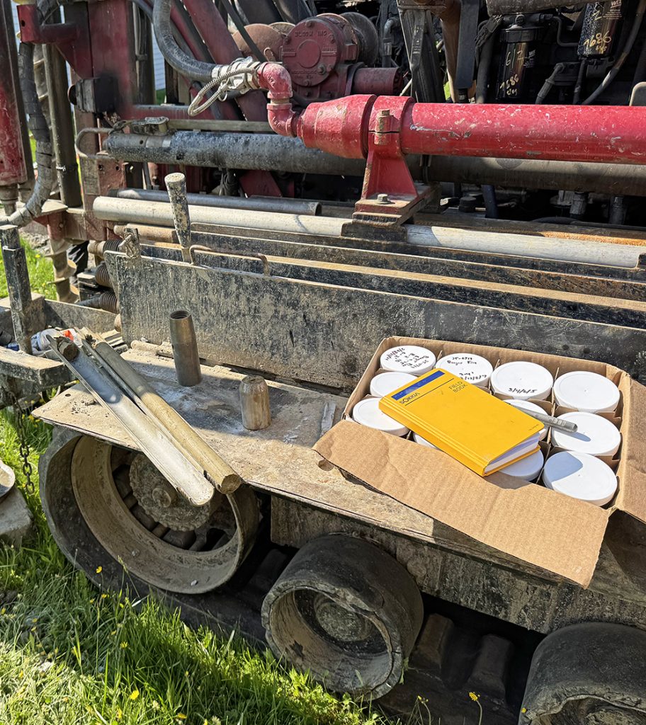 A split spoon sampler, geotechnical engineer's log book and sample jars on the shelf of a geotechnical drill rig.