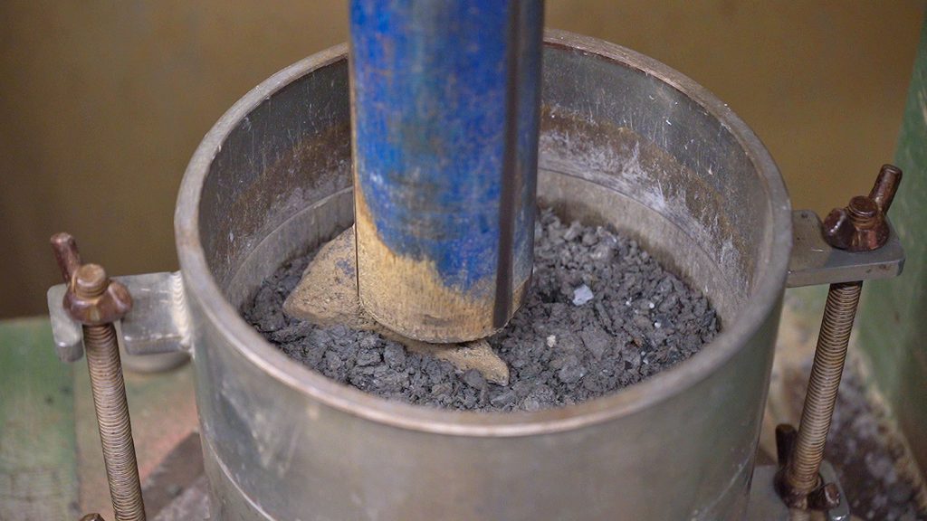 A close-up of a Moisture–Density Relationship test being performed on soil in a construction materials testing lab.