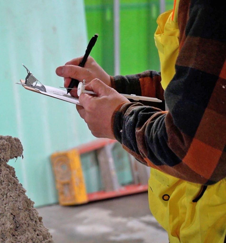 A special inspector writing information on a clipboard.