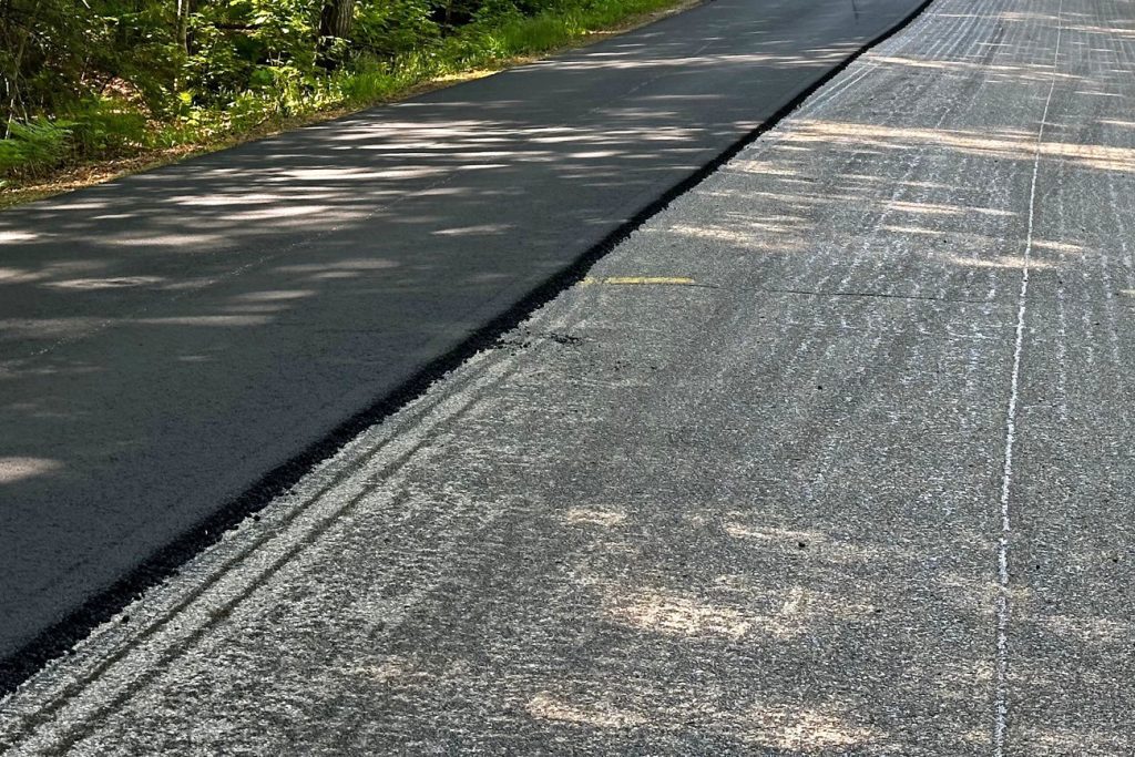 A stretch of road that is freshly paved on one side.