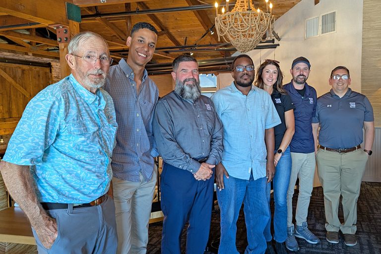 The Emerging Leaders graduates with former and current company leaderships standing together in an indoor space.