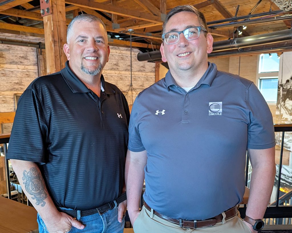 Sean Giroux with his Emerging Leaders mentor, Derek Mello, standing next to each other and smiling in an indoor space.
