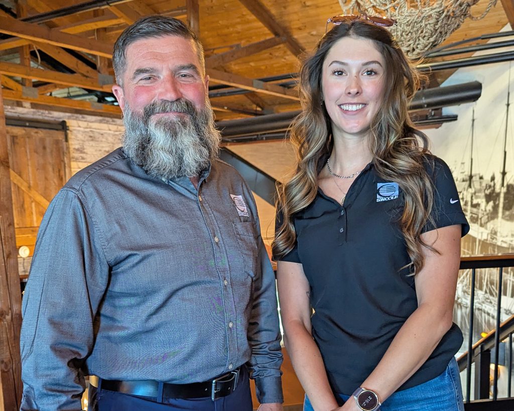 Emma Dennis with her Emerging Leaders mentor, Bob Chaput, standing next to each other and smiling in an indoor space.