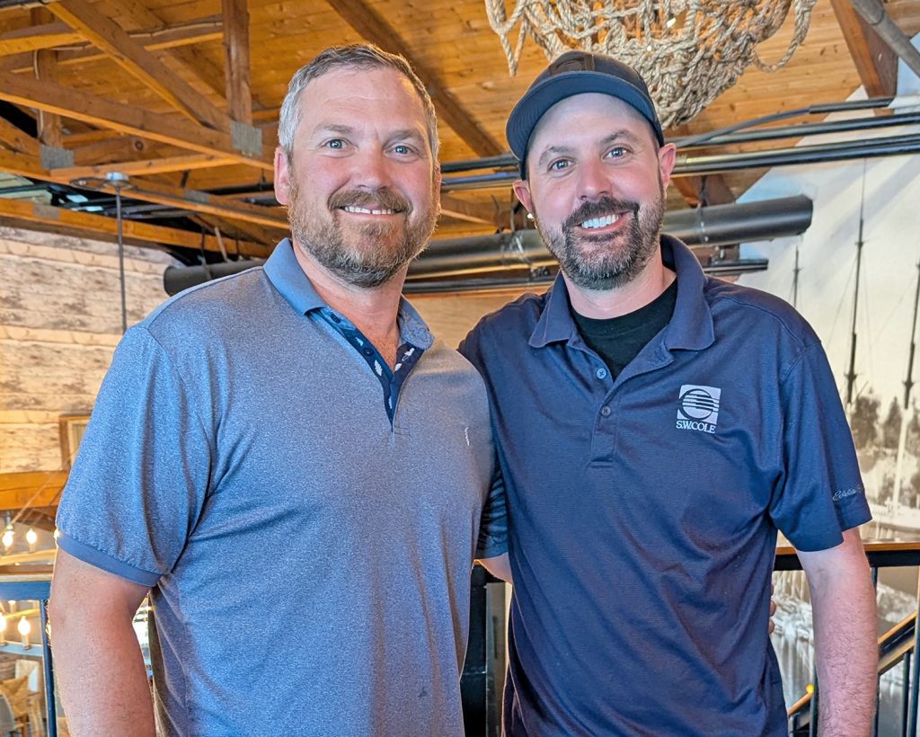 Heath ONeill with his Emerging Leaders mentor, Mike St. Pierre, standing next to each other and smiling in an indoor space.