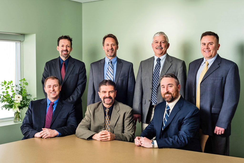 A group photo of the S.W. Cole Board of Directors, in formal business attire, some seated and some standing in an interior space.