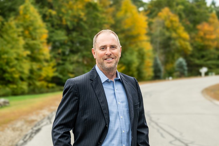 Photo of Chad Michaud with fall leaves and a road in the background.